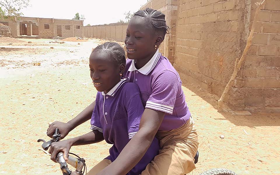 sisters share a bike in Mali