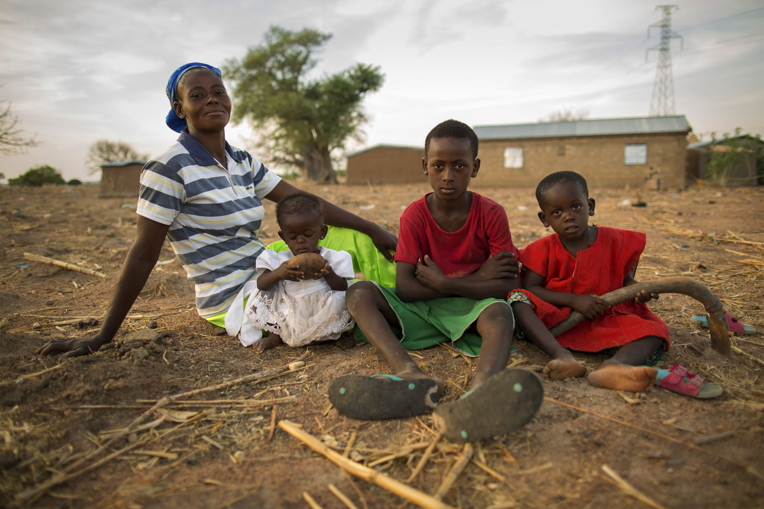 Nyaamah sits with her children Nma, Prince and Edmond on their sometimes profitable farmland. Photo by Jake Lyell for CRS