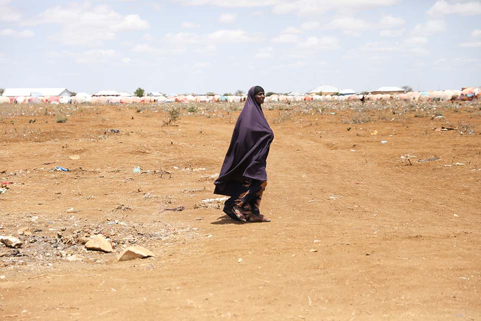 Somali woman walks along parched ground 