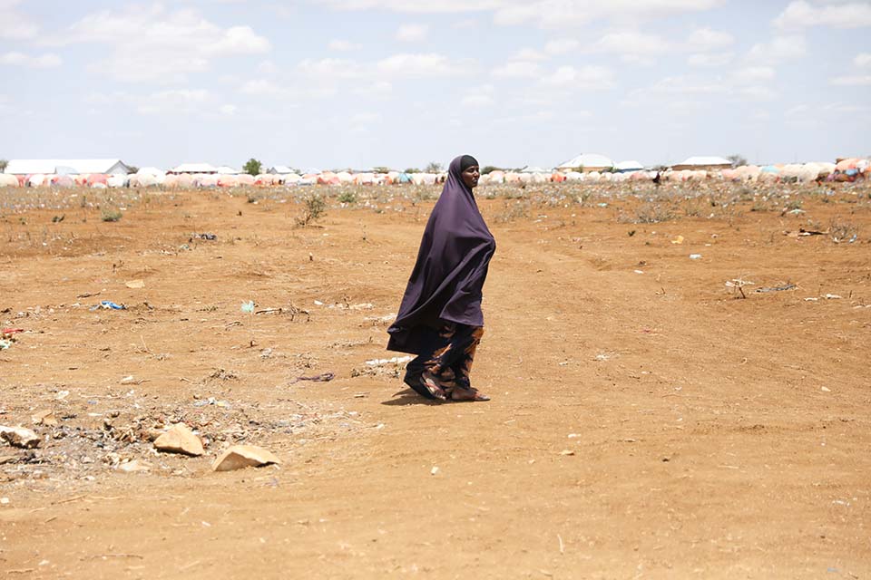 Somali woman walks along parched ground