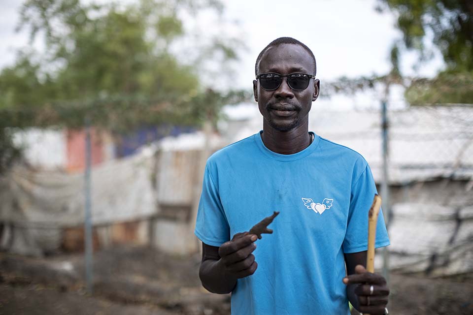 South Sudanese man in sunglasses facing camera and holding clay gun