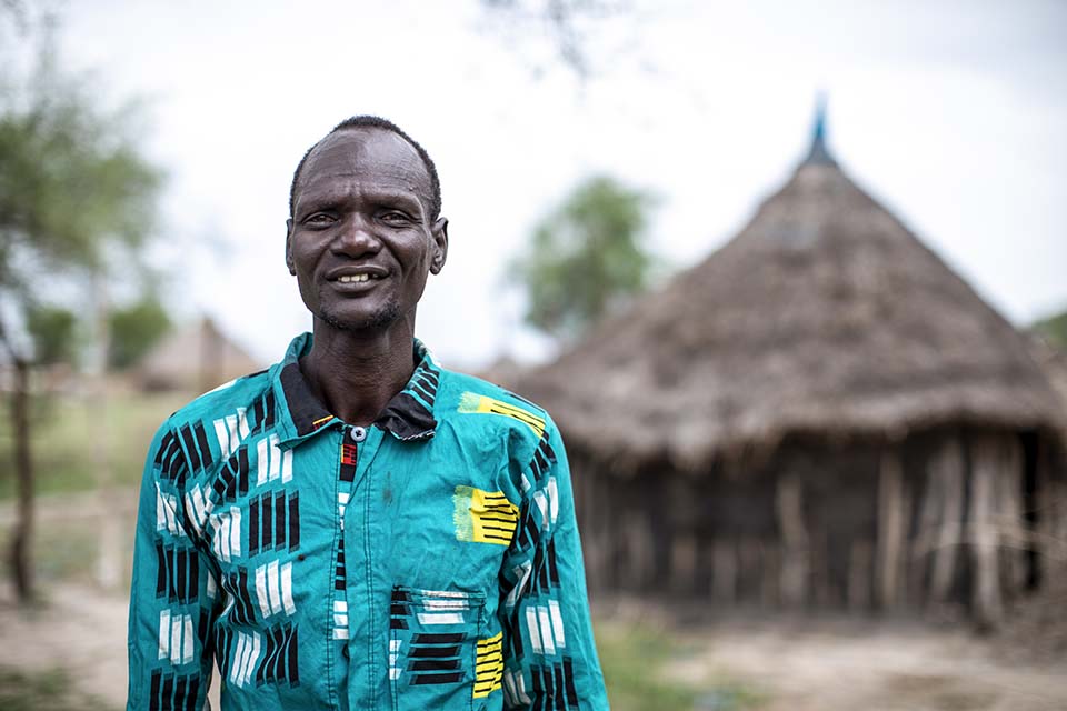 South Sudanese man standing outside a tukul