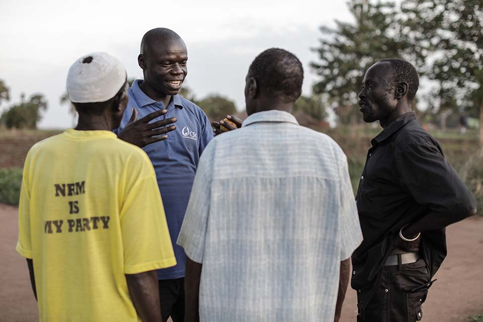 South Sudanese refugee talking with 3 men in Uganda