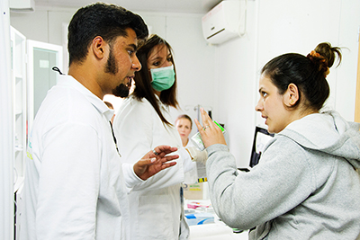 CRS Serbia’s Kemal El Shairy, left, translates for a refugee seeing a doctor at a border crossing. Photo by Kira Horvath for CRS