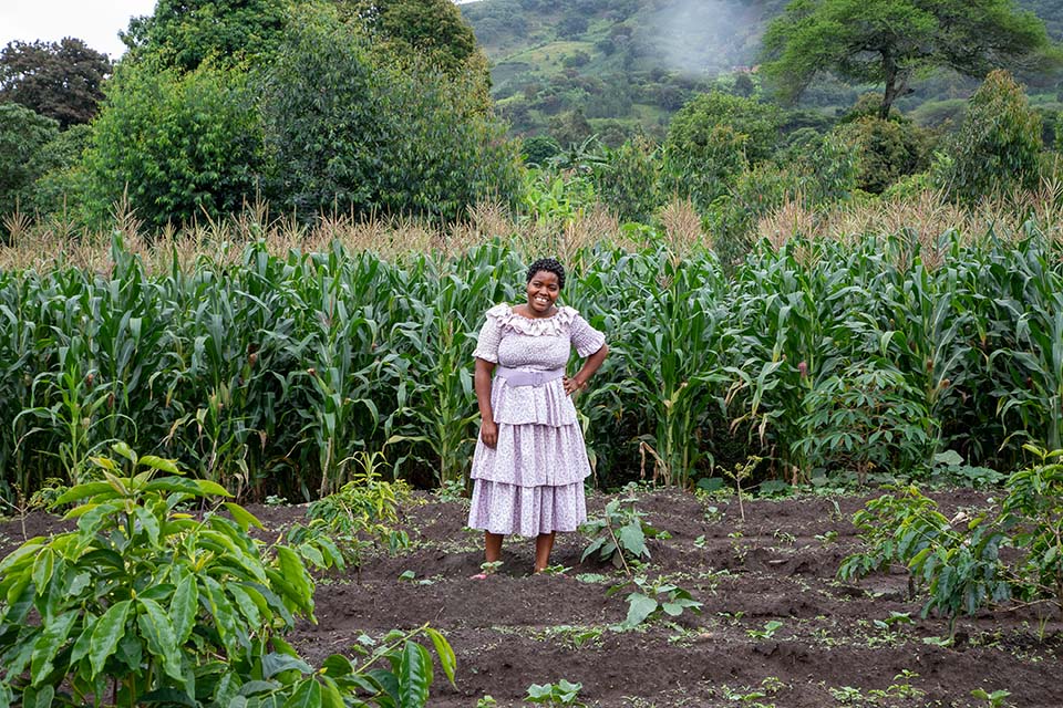 Tanzania woman standing in corn field facing camera, smiling