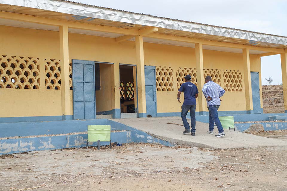 two men approach school building in Cameroon