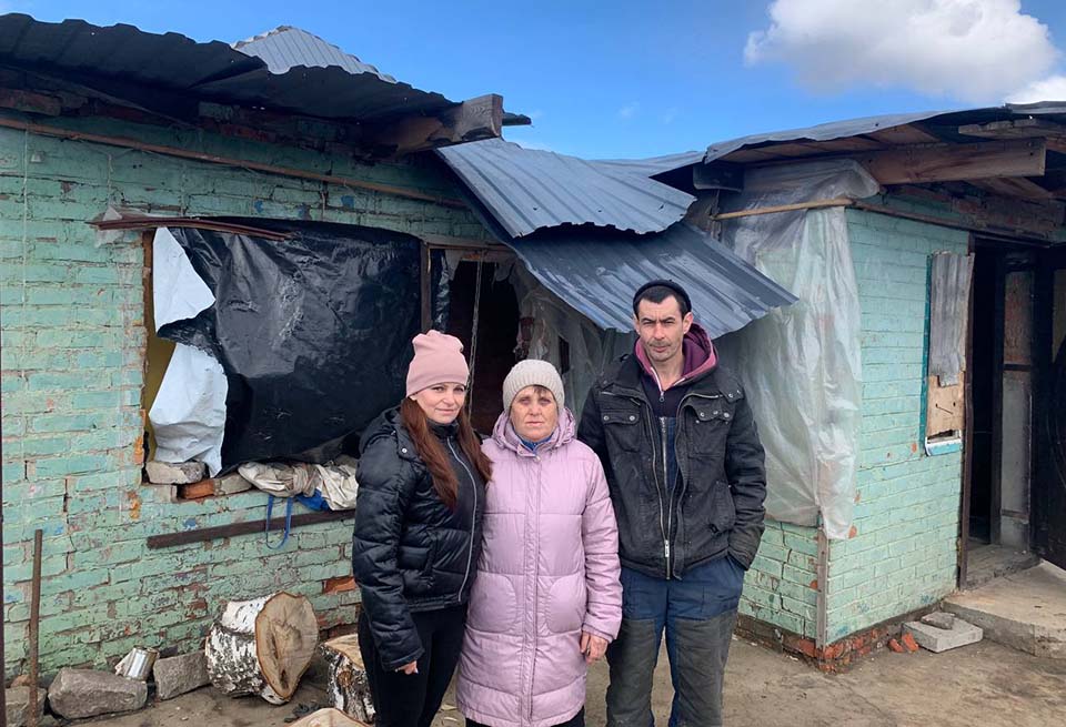 Ukraine family outside damaged home 