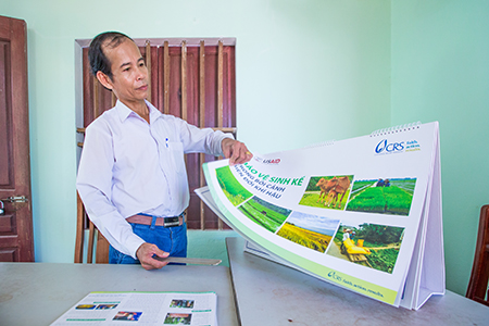 Photo by Lisa Murray for CRS TSG member Vo Tan Sanh shows some of the flip charts he uses during livelihood resilience training that has also benefited 200 farmers from communities outside the scope of the project.