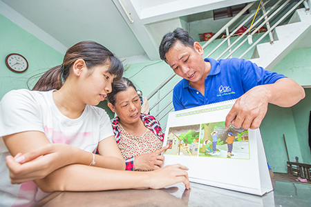 Photo by Lisa Murray for CRS Thuong explains flood evacuation procedures to Dinh Thi Xuan and daughter Thao, who have stopped by the local community center to seek the support group’s advice.