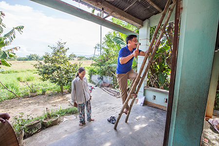 Photo by Lisa Murray for CRS A local support group representative, Thuong, makes one of his regular house visits to ensure Phuoc’s new roof is standing to up the increasingly severe climate change-related storms and natural hazards that pound central Vietnam.