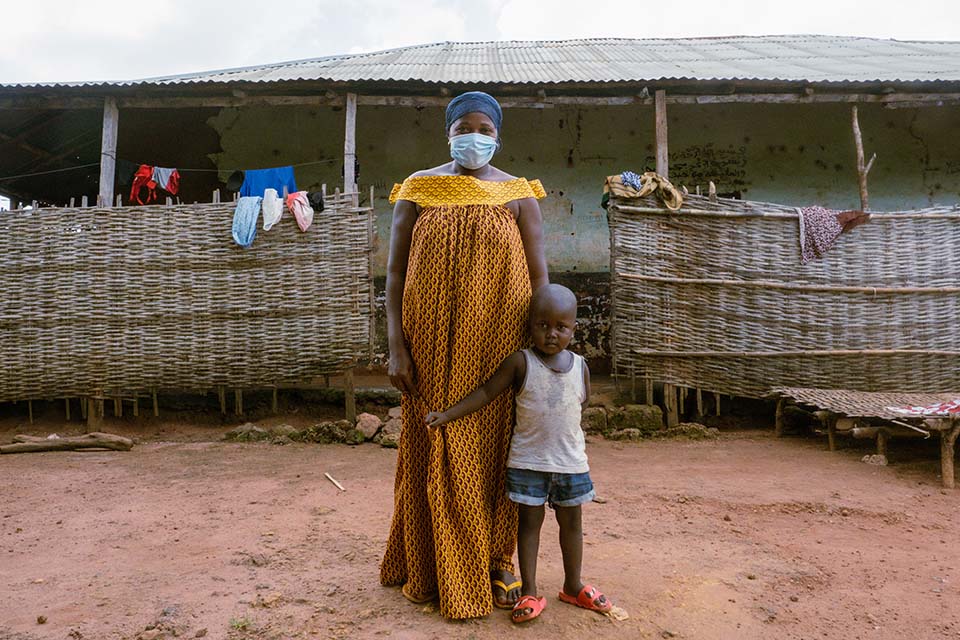 woman and her son stand near a market in Guinea Bissau