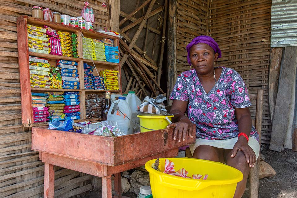 woman facing camera sits in small shop in Haiti