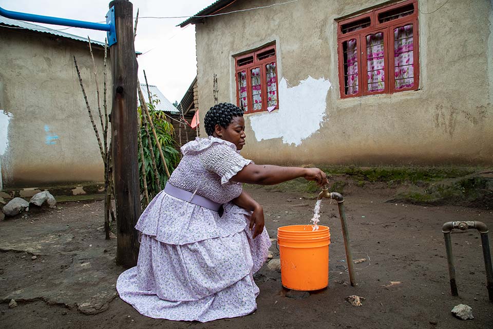 woman fills bucket from water tap in Tanzania 
