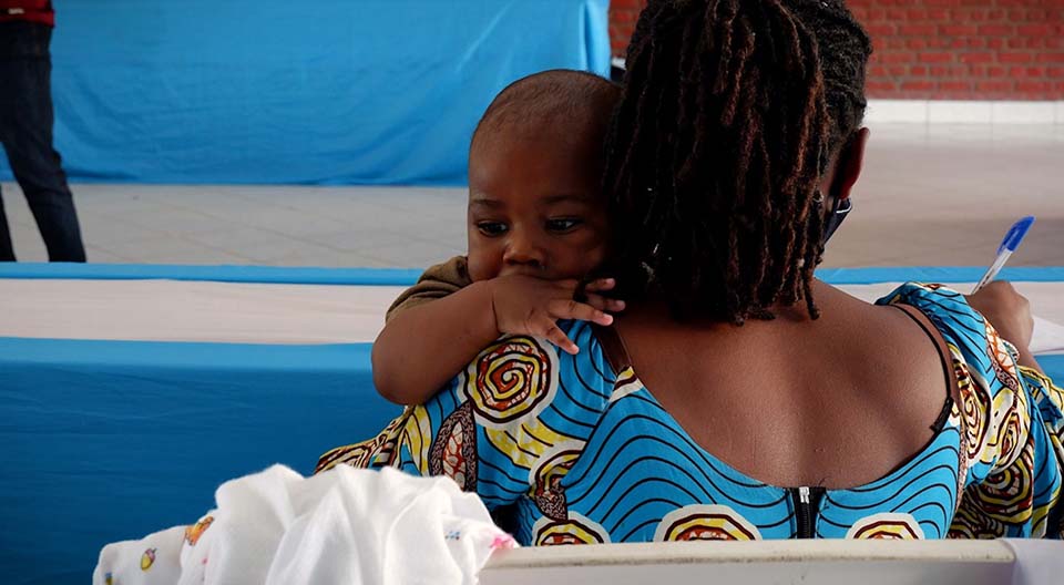 woman holds a child during a conference in Rwanda