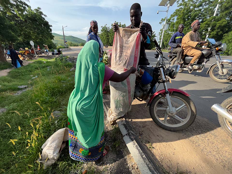 woman in Cameroon buying vegetables from a moto-produce operator