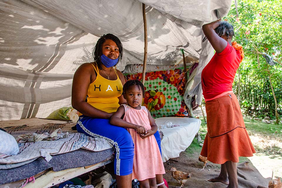 woman sits with her daughter in temporary shelter in Haiti