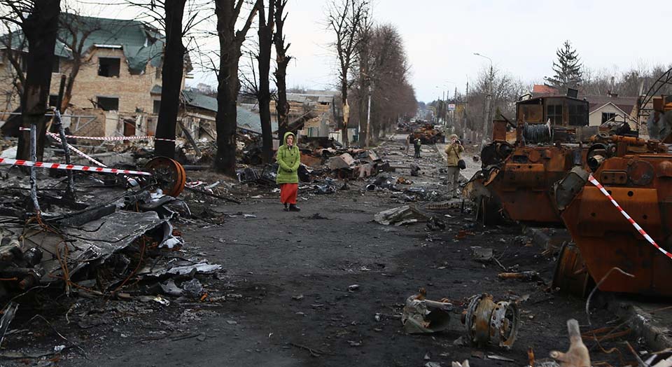 woman stands amid destruction in Ukraine