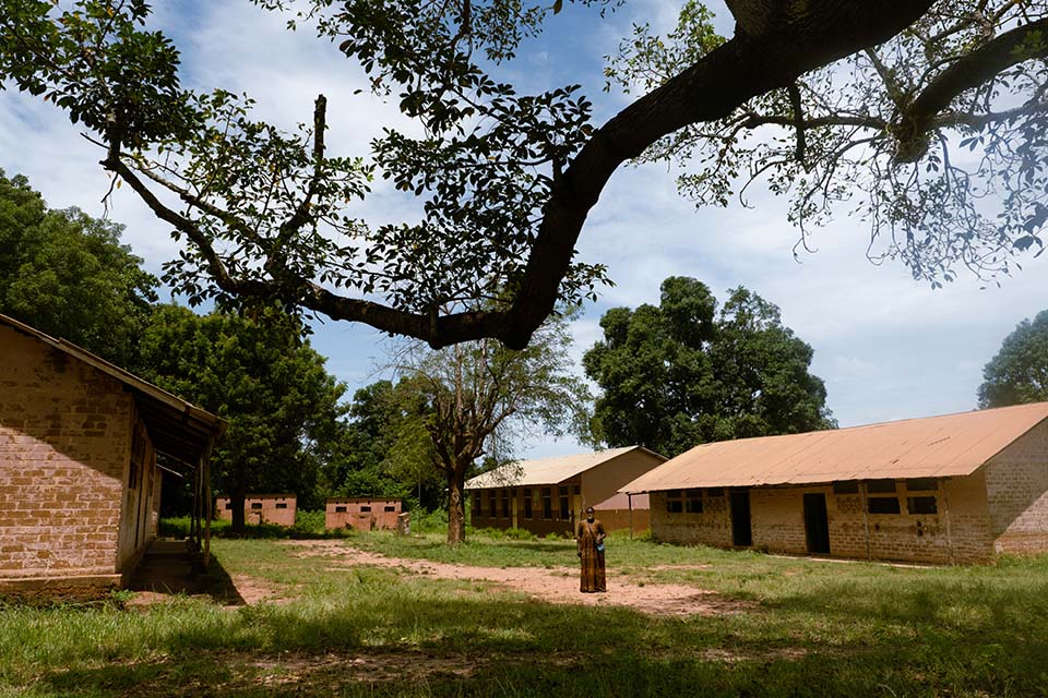 woman stands outside a school in rural Guinea Bissau