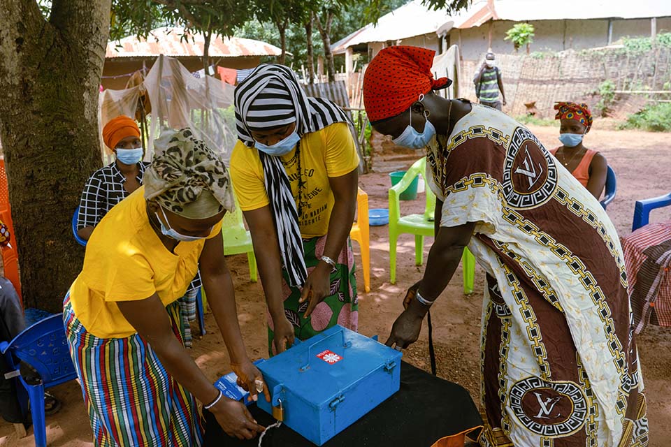 Women secure a box holding funds from their community-based savings group 