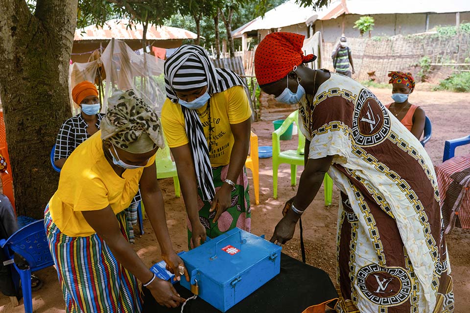 Women secure a box holding funds from their community-based savings group