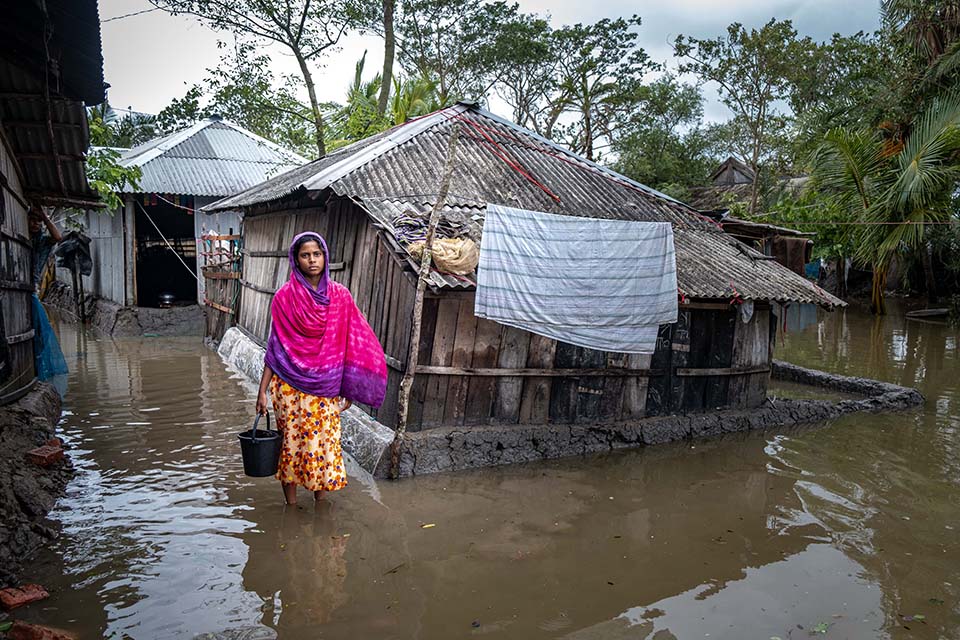 young woman wades through flood water in Bangladesh