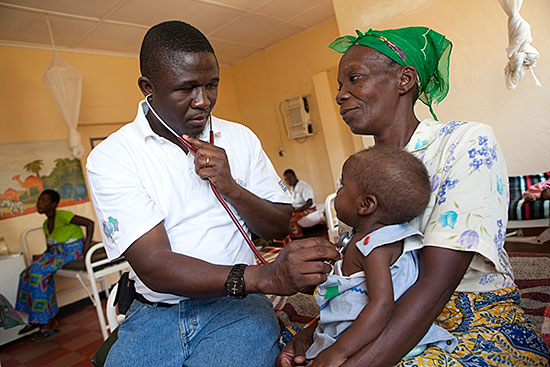 Josphat, who recently tested positive for HIV, receives care from Dr. Kasong Tshijing (left) at St. Theresa Mission hospital, an AIDS Relief-supported hospital in Zambia. Photo by Jake Lyell for CRS