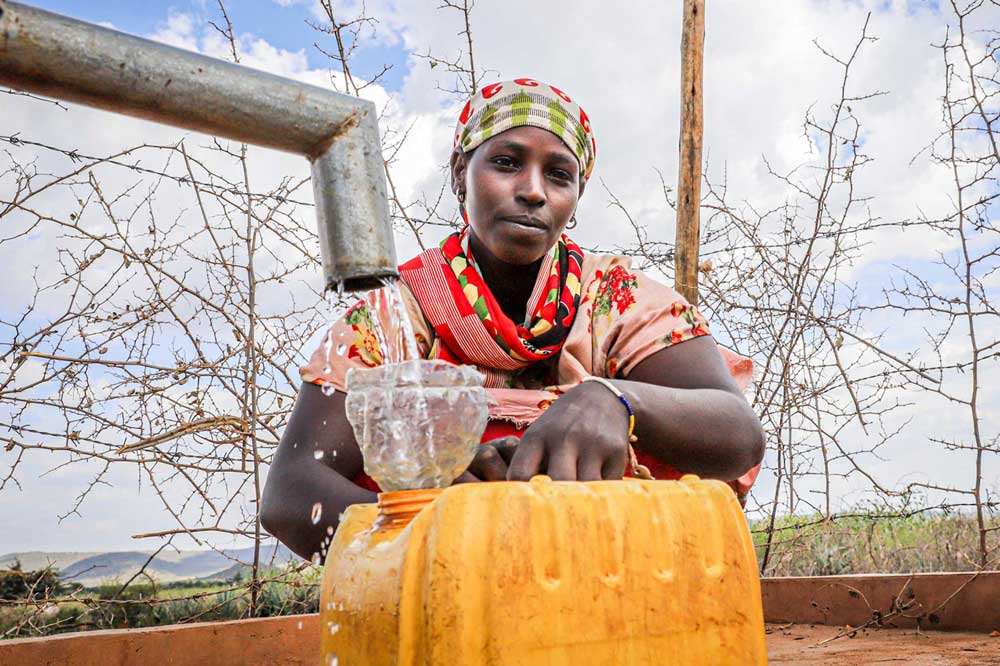 Woman filling a yellow bin with water.