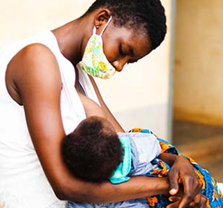 Woman with a face mask holding a baby.