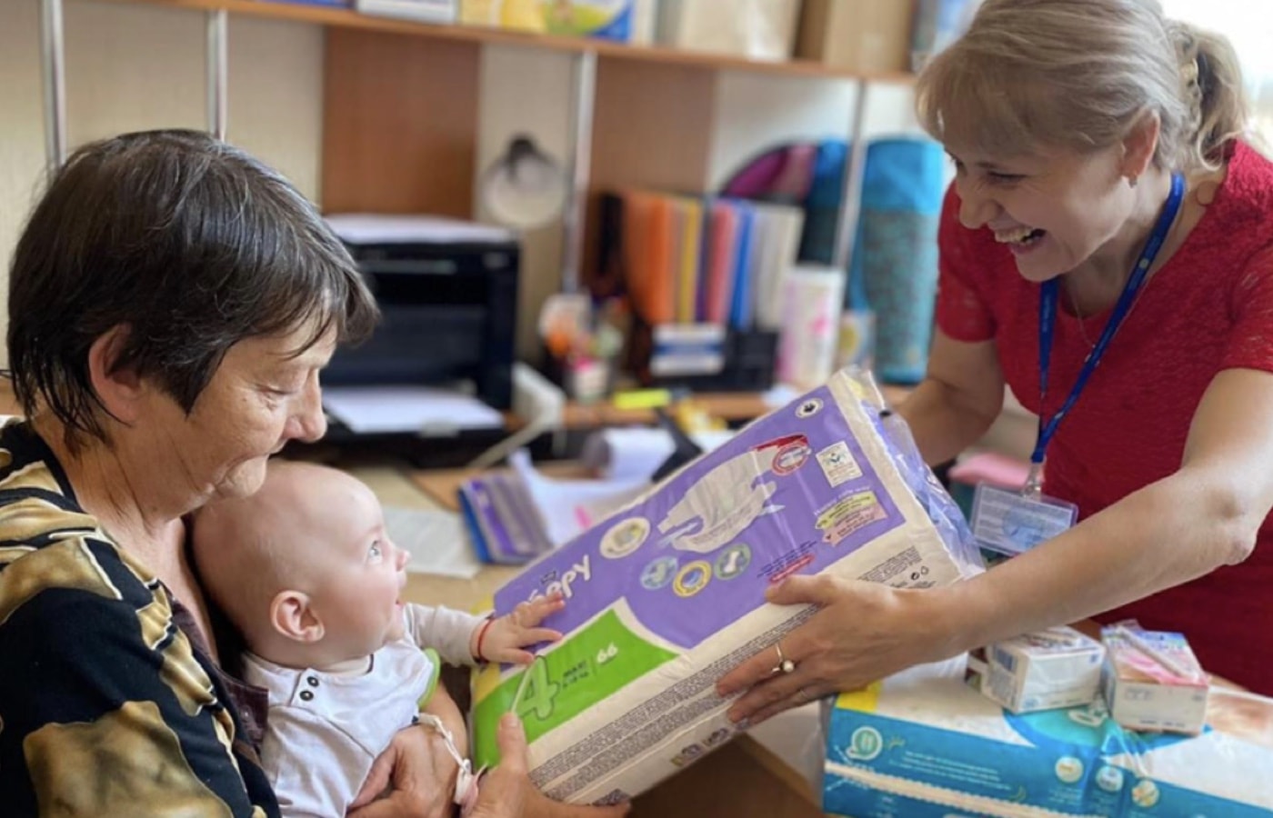 Caritas team member gives mother and baby diapers.