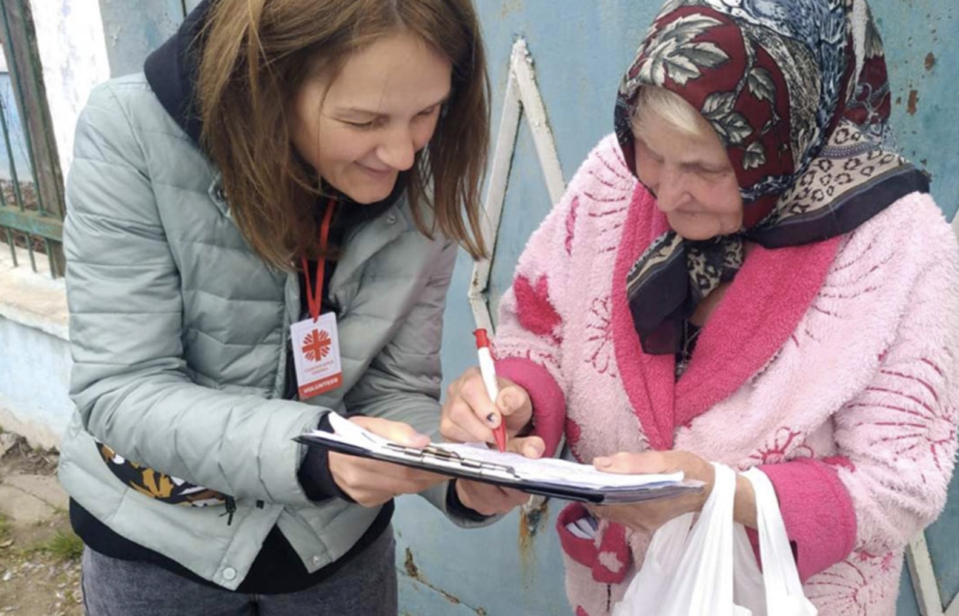 Caritas team member helps Ukrainian woman fill out form.
