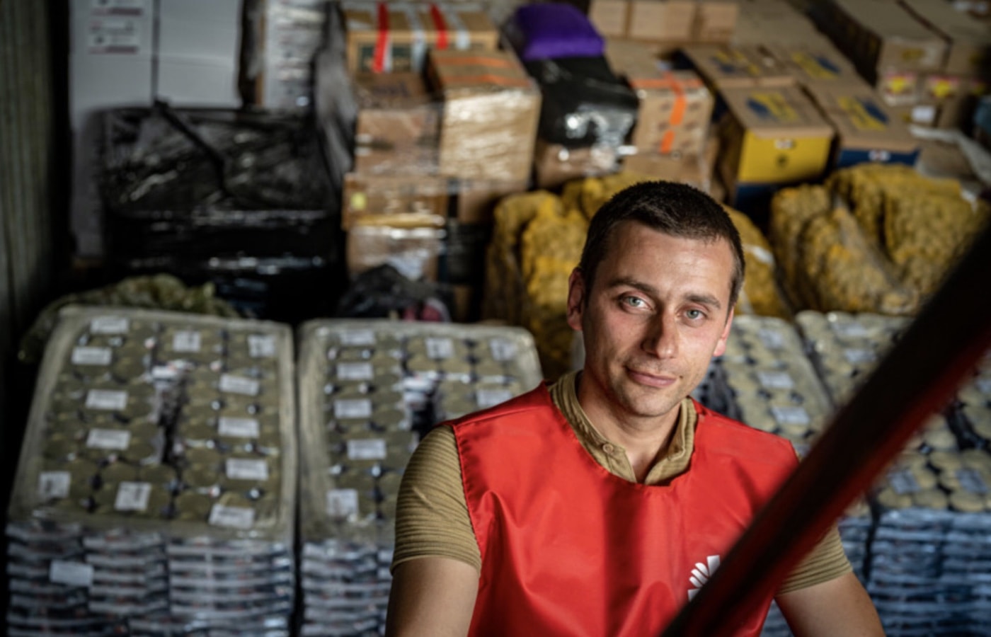 Caritas team member in front of boxes of food and supplies.