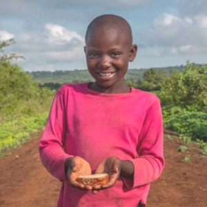 Child on dirt road holding bread