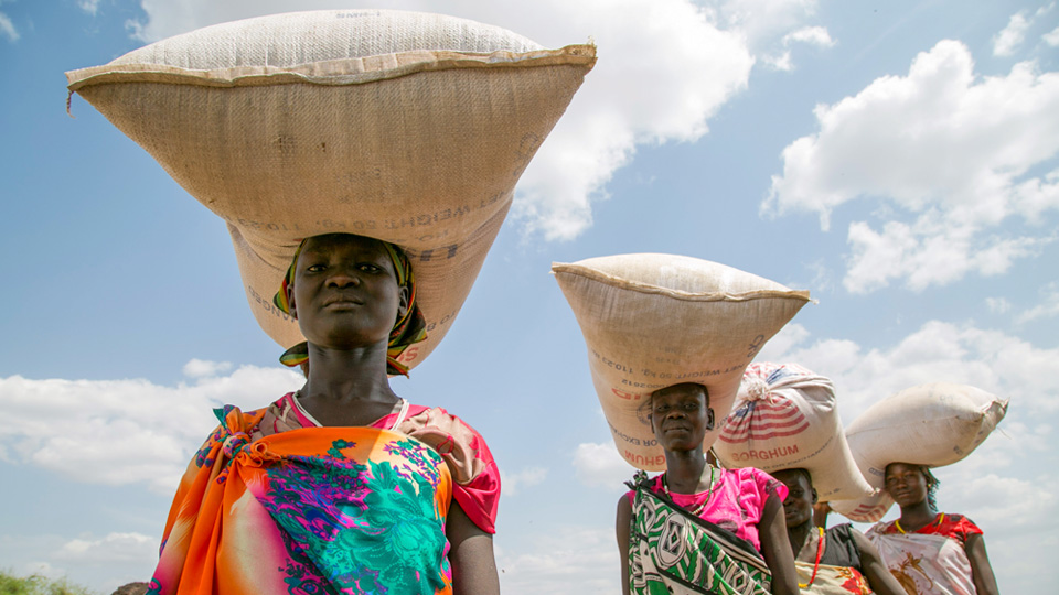 Women carrying supplies over their heads.