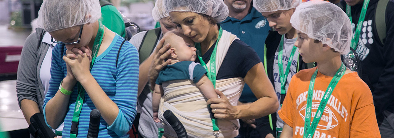 Attendees at the World Meeting of Families, pray together before a CRS Helping Hands event.