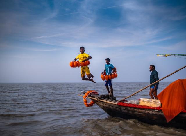A boy jumping in the water from a boat.