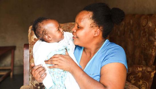 mother seated in a chair lovingly holds infant