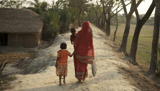 woman holding a baby and walking with girl