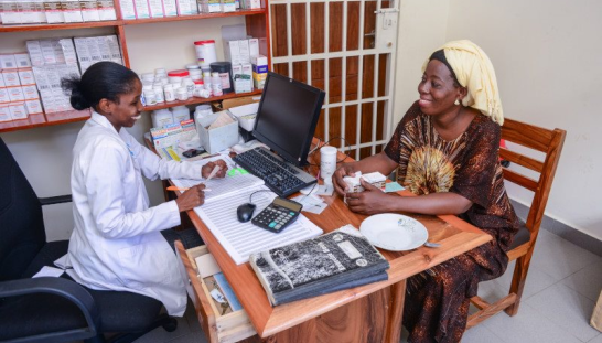 A nurse and a woman sitting at a table.