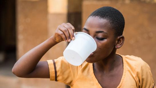 A girl drinking water from a plastic cup.