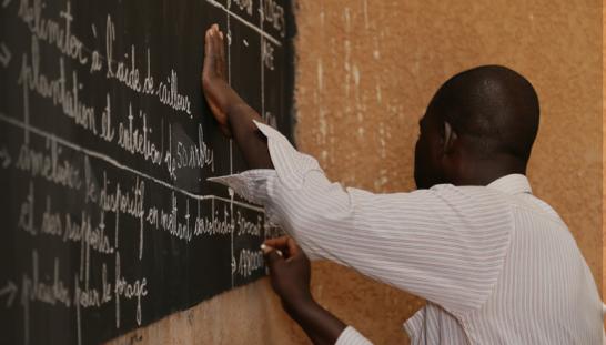 A man writing on a school board.
