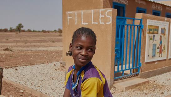 A young girl in front of a building.