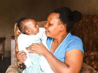 mother seated in a chair lovingly holds infant 