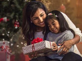 A woman and a child in front of a Christmas tree.