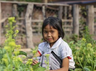 A young girl sitting by flowers.