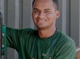 young man in green shirt working with green machine with tubing