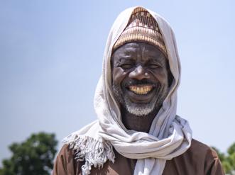 A man in traditional clothes, smiling.