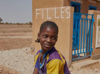 A young girl in front of a building.