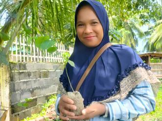 Woman holds a growing sapling plant.