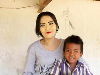 A mother and son sitting close together smiling. 