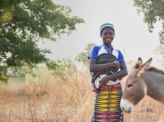 A young woman standing next to a donkey.